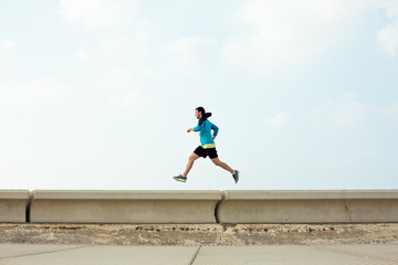 athletic sportsman running over concrete border near the ocean