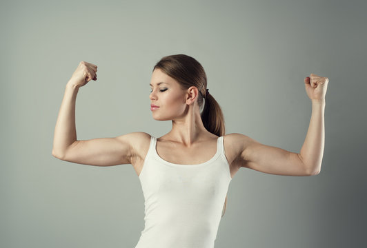 Young sporty female showing her biceps. Concept of strength.