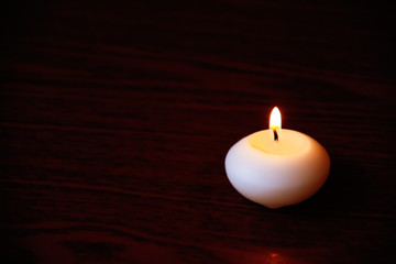 Obraz na płótnie Canvas Single candle on a dark wooden table. Close up shot with selecti