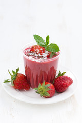 strawberry milkshake in a glass on white table, vertical