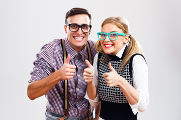 Happy nerdy couple showing thumbs up - obrazy, fototapety, plakaty