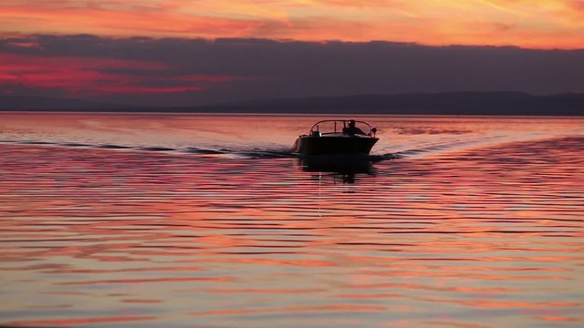 motorboat approaching the camera at sunset in silhouette