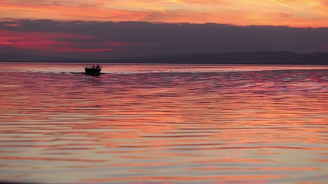 motorboat approaching the camera at sunset in silhouette