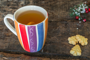 A cup of hot tea with lemon on rustic wooden table, close-up