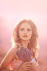Naklejka premium Sensual Woman Lying on a Meadow with Violet Flowers.