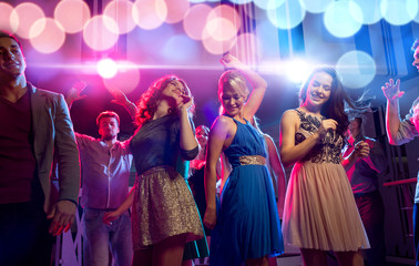 smiling friends dancing in club