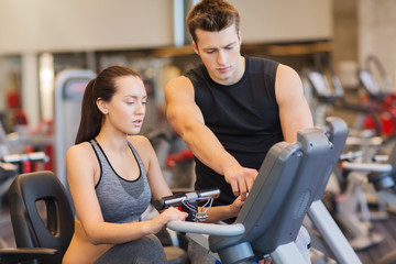 Fototapeta premium woman with trainer on exercise bike in gym