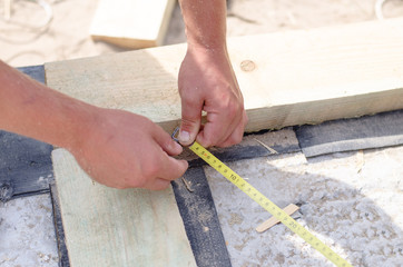 Hands of a carpenter taking a diagonal measurement