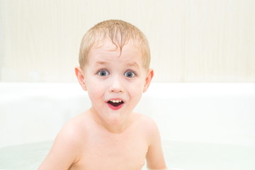 The little boy bathes in a bathroom and looks in amazement at