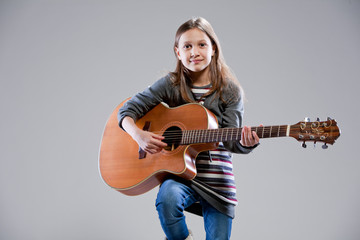 Fototapeta premium little girl playing acoustic guitar