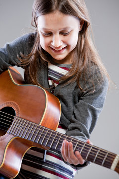 little girl playing acoustic guitar