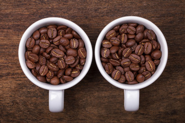 cup of coffee beans on the brown wooden background..