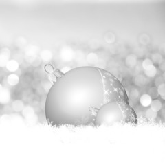 zwei silberne Kugeln liegen im weihnachtlichen Schnee