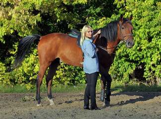 Blonde woman leads a racehorse in the paddock