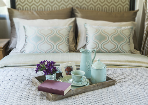Decorative tray with book,tea set and flower on the bed