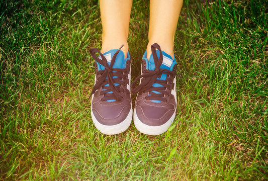Girl sitting shoes closeup, green grass, woman fitness
