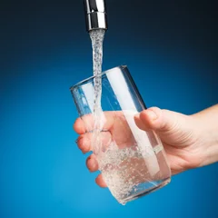 Meubelstickers hand een glas water uit de filterkraan gieten © nikkytok