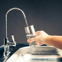 hand pouring a glass of water from filter tap