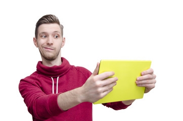 Amusing young guy holding tablet pad and looking at the screen