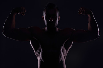 Silhouetted muscular man showing his biceps