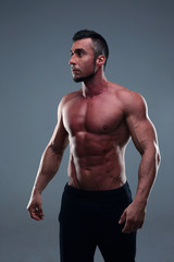 Fototapeta premium Young muscular sportsman standing over gray background
