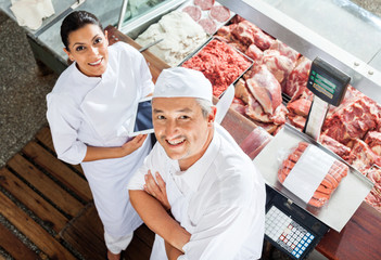 Happy Butchers Standing At Butchery Counter