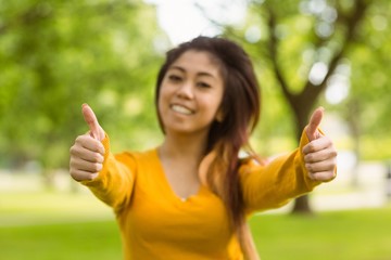 Beautiful woman gesturing thumbs up in park