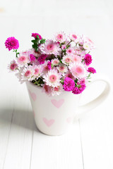 Beautiful flowers in cup on table close-up