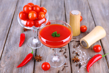 Tomato juice in goblet and fresh vegetables on wooden