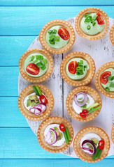 Fototapeta premium Tartlets with greens and vegetables with sauce on tray on table