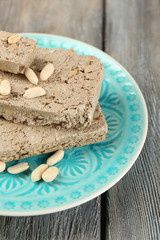 Sunflower halva with peanuts on plate, on wooden background