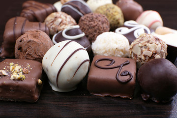 Assorted chocolates on the dark wooden smooth background