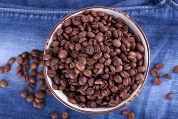 bowl of coffee beans stands on jeans background
