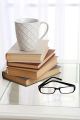 Tabletop with pile of books, cup and glasses
