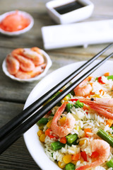 Boiled rice with shrimps and vegetables on wooden background