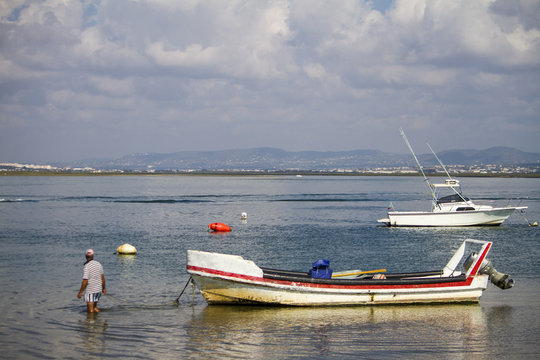 View of an traditional fishing boat being pulled by a man.