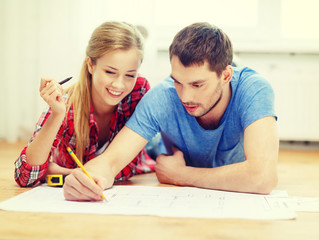 smiling couple looking at blueprint at home