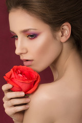 Close-up portrait of young beautiful woman holding red rose