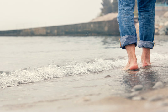 Close up image barefoot man legs in the sea surf