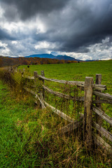 Fototapeta na wymiar Fence in a farm field and view of Grandfather Mountain along the
