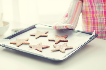 close up of woman with cookies on oven tray