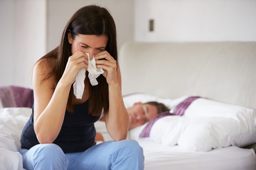 Woman Suffering From Depression Sitting On Bed And Crying