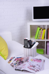 Many remote control devices on sofa in room