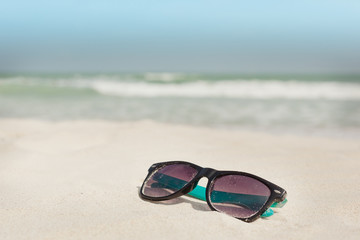 Fototapeta na wymiar Sunglasses in the sand on the seashore. vacation time