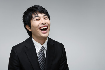 흰 배경 스튜디오에서 검은 정장을 입고 제스처를 취하는 젊은 남성 