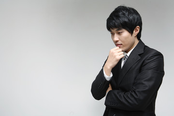 흰 배경 스튜디오에서 검은 정장을 입고 미소를 지으며 제스처를 취하는 젊은 남성 