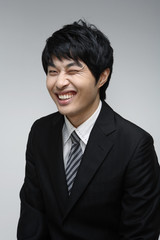 흰 배경 스튜디오에서 검은 정장을 입고 미소를 지으며 제스처를 취하는 젊은 남성 