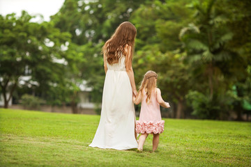mother and daughter walking in the park, happy at sunset
