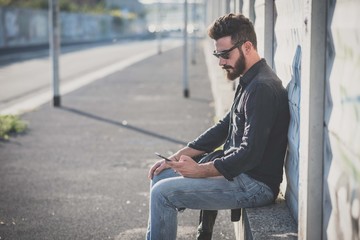Obraz premium young handsome attractive bearded model man using smartphone
