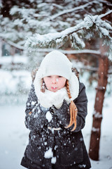 cute happy child girl blowing the snow in winter forest